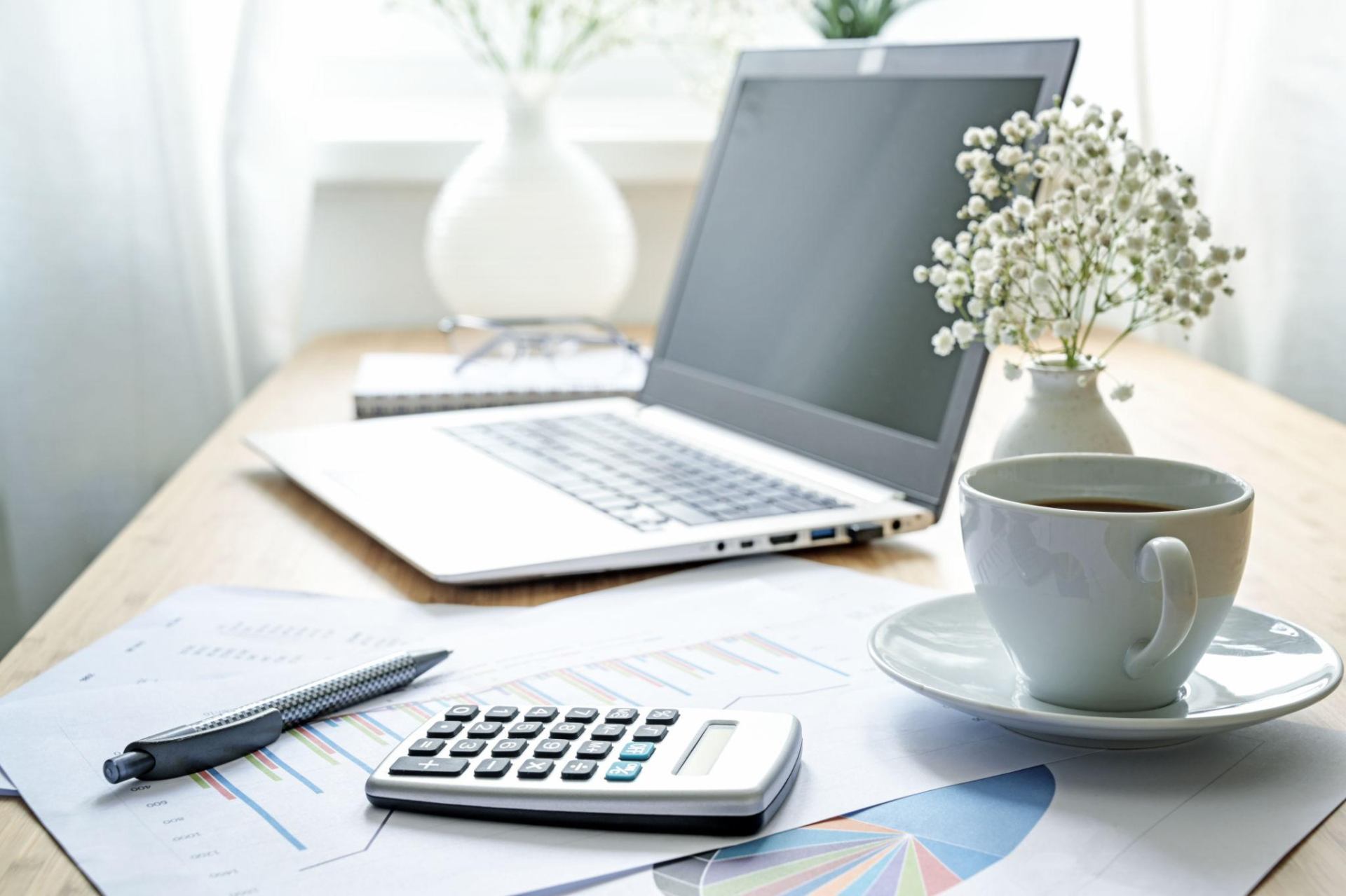 Organized bookkeeping workspace with laptop, calculator, and coffee